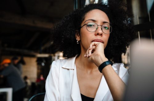 Young african american woman using laptop computer while sitting by table in cafe